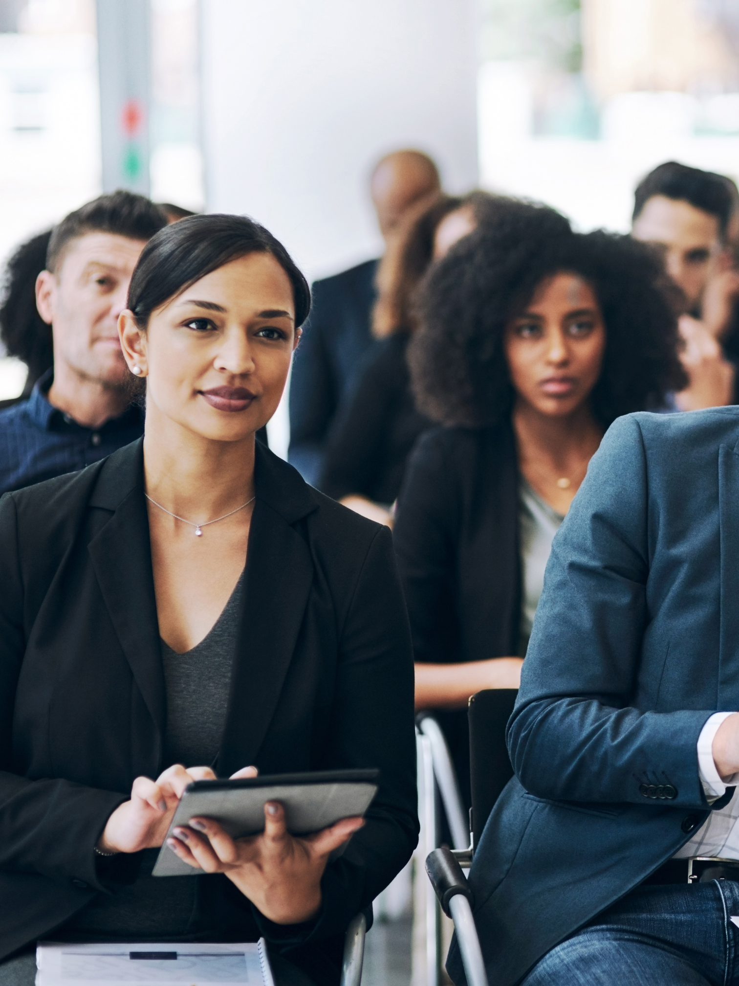 A woman seated around other professionals is attentively watching a presentation